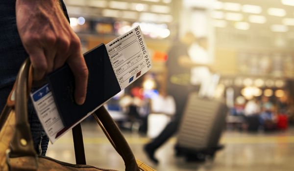 A person holding travel documents and walking at the airport