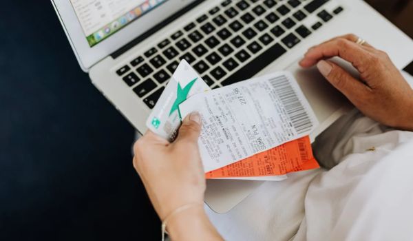 Person using a computer and holding a credit card and receipts